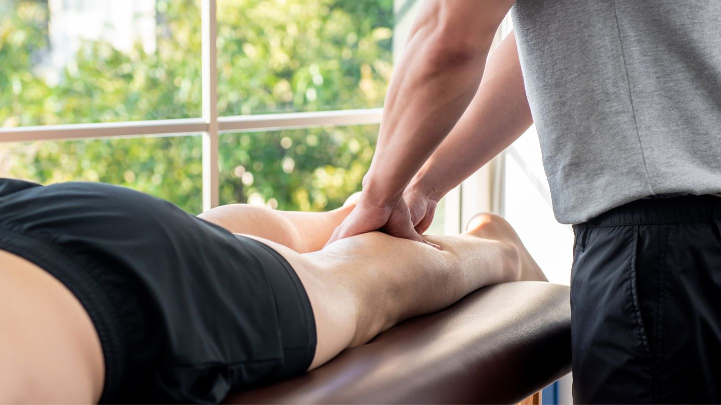 Sports massage therapist performing deep tissue therapy on an athlete's leg muscle for recovery and tension relief.